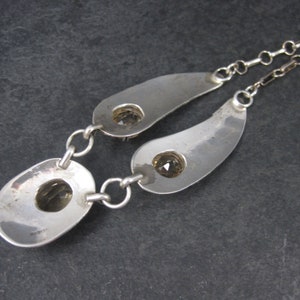 May include: Silver necklace with two teardrop-shaped pendants, each featuring a clear gemstone. The necklace has a delicate chain.