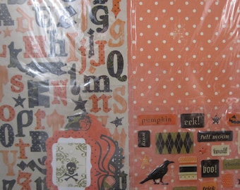 May include: Halloween-themed scrapbook paper and embellishments. Includes orange polka dot paper, alphabet letters, and decorative elements with words like "pumpkin," "boo," and "trick or treat." A skull and crossbones design is also visible.