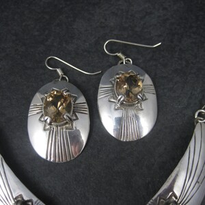 May include: A silver necklace and earrings set with a crescent moon design and a brown gemstone in each piece.