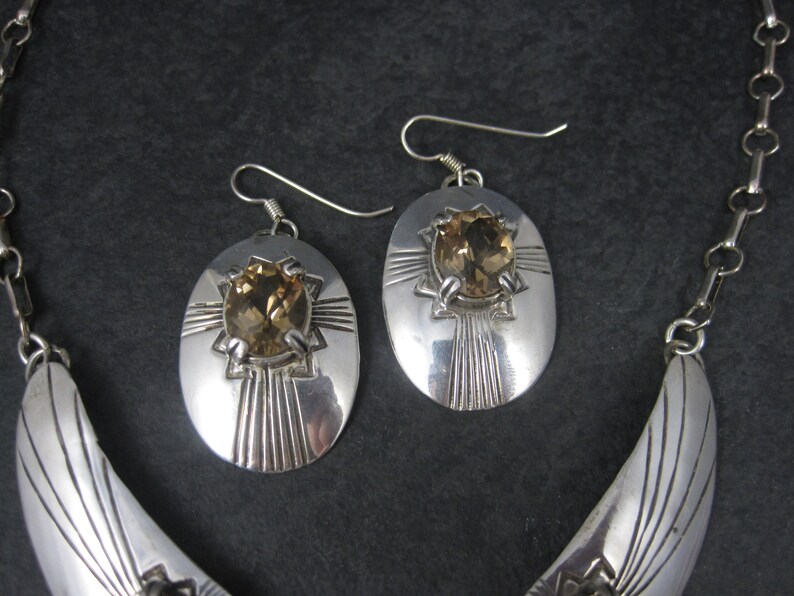 May include: A silver necklace and earrings set with a crescent moon design and a brown gemstone in each piece.