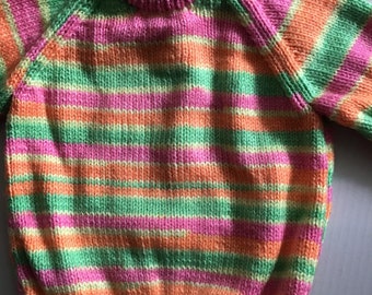 This girls' jumper/sweater fits a 20 inch chest or a 9 month - 18 month old. It is knitted in striped yarn in pink, orange,green and lemon.