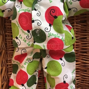 May include: A white pajama set with red and green ornaments. The ornaments have the text "jingle bells" and "holiday cheer" on them.