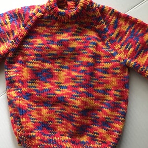 This jumper/sweater fits a 20 inch chest or a 9 month 18 month old. It is knitted in variegated yarn of red, blue and yellow. image 1