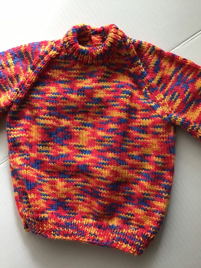 This jumper/sweater fits a 20 inch chest or a 9 month 18 month old. It is knitted in variegated yarn of red, blue and yellow. image 1