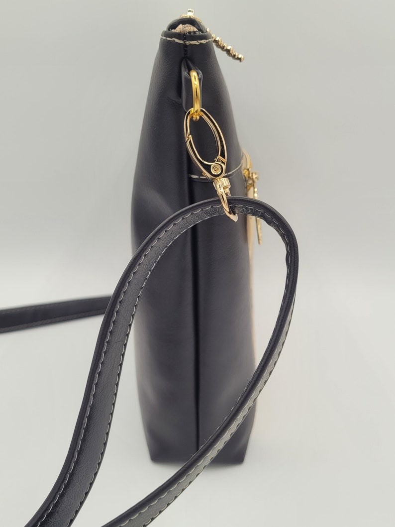 May include: A black crossbody bag with a gold zipper and a gold chain strap. The bag has a flap closure and a small pocket on the front.