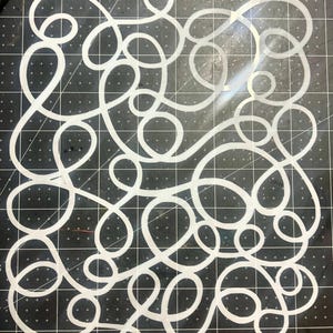 May include: White, swirling, abstract design on a black grid background. The design features continuous, looping lines of varying sizes and shapes, creating a dynamic and intricate pattern. The image is a close-up, highlighting the details of the design.