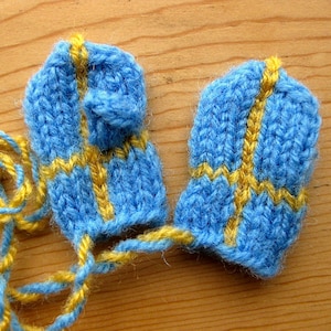 May include: Two blue knitted fingerless gloves with yellow stripes. The gloves are connected by a yellow yarn.