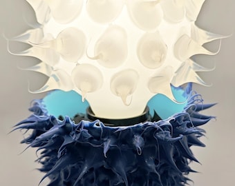 Tha blue plant Ubo light. white globe Ubo in a plant table lamp. all hand made with coloured silicone bt Yuval Dor 2025.