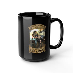 May include: A black ceramic mug featuring a graphic illustration of a warrior holding a war hammer on a ship deck. The text reads: WHO NEEDS A MAN TO PROTECT YOU, WHEN YOU HAVE A WAR HAMMER. The design is framed by decorative tan banners.