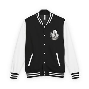 Op de afbeelding: Zwart-witte varsity jas met een knoopsluiting en witte mouwen. De jas heeft een grafisch ontwerp op de borst. De manchetten en kraag hebben witte strepen.