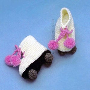 May include: Two handmade crochet roller skates. The skates are white with black accents and brown wheels. Each skate has a pink pom-pom detail and pink laces. The background is a solid light blue.