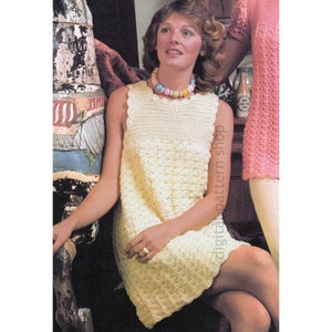 Puede incluir: Un vestido de crochet sin mangas con un escote festoneado. El vestido es de color amarillo claro y tiene un patrón texturizado. La modelo lleva un collar de cuentas de colores.