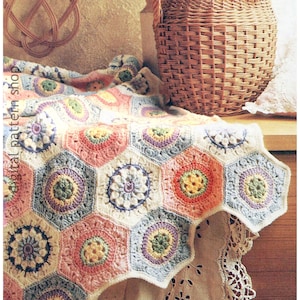 Puede incluir: Una manta de ganchillo con un diseño hexagonal en tonos pastel de rosa, azul, amarillo y verde. La manta se muestra, con una cesta de mimbre en el fondo. El texto "digital pattern shop" es visible. Es un artículo hecho a mano.