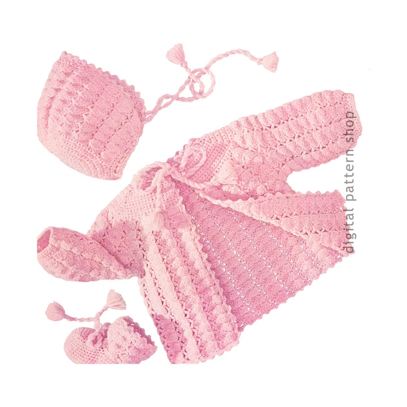 Pu&ograve; includere: Un set di abbigliamento per neonati in crochet rosa composto da un cardigan, un cappello e dei booties. Il cardigan ha una chiusura a cravatta e un delicato motivo a crochet.