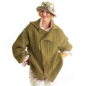 May include: A green knitted cardigan with a button closure and a wide collar. The cardigan is worn by a person wearing a white shirt and a green hat with pins.