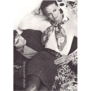 May include: A black and white photo of a couple posing together. The woman is wearing a white shirt with a patterned scarf tied around her neck. The man is wearing a dark jacket and a light-colored shirt. The woman is sitting on a couch with her arm resting on the back of the couch. The man is sitting next to her with his arm around her waist. The photo is taken from a slightly elevated angle.