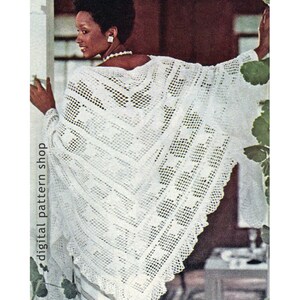 May include: A white crochet shawl with a lacy pattern. The shawl is draped over a person's shoulders and has a scalloped edge.