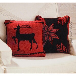 May include: Two square knitted throw pillows. One is red with a black deer silhouette, the other is black with a red snowflake design. Both pillows have a red border and are on a white couch.