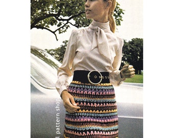 Peut inclure: Une jupe en crochet avec un motif rayé coloré dans les tons de rose, bleu, jaune et marron. La jupe est portée avec un chemisier blanc et une ceinture noire avec une grande boucle dorée. La jupe est de style vintage et serait un excellent ajout à toute garde-robe.