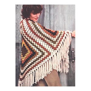 May include: A crocheted shawl with a geometric pattern in shades of brown, orange, green, and white. The shawl has a fringe border.