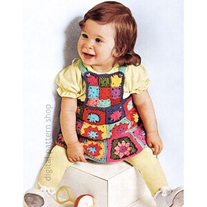 May include: A young child in a vibrant, hand-crocheted dress with a patchwork design. The dress is made up of colourful squares in shades of red, blue, green, and pink. The child is also wearing a yellow top and tights. The text "digital pattern shop" is visible.