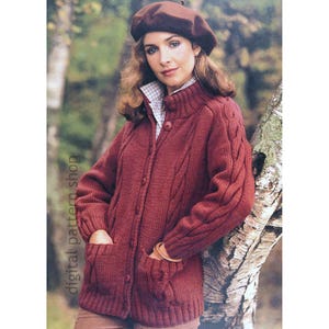May include: A woman wearing a burgundy cable-knit cardigan with a matching beret. The cardigan has a high collar, button closure, and front pockets. The image has the text "digital pattern shop" on the left side.