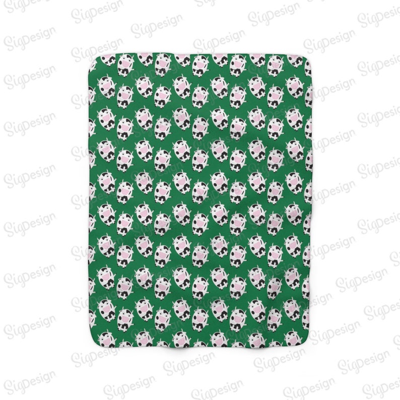 May include: A green fabric with a repeating pattern of white and black cows with pink noses. The cows are facing forward and have a simple, cartoon-like design.