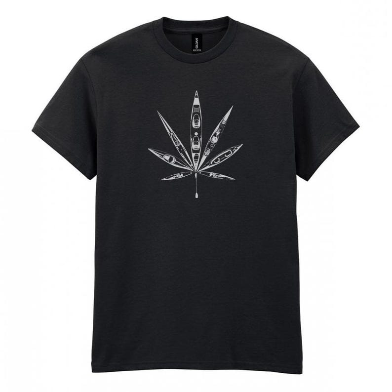 May include: Dark gray t-shirt featuring a white graphic of a cannabis leaf. The leaf design is composed of kayak illustrations. The shirt is made of a soft, comfortable material.