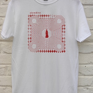 Puede incluir: Camiseta blanca con un estampado rojo de un laberinto con una figura en el centro. El texto "slowdive" está impreso sobre el laberinto.