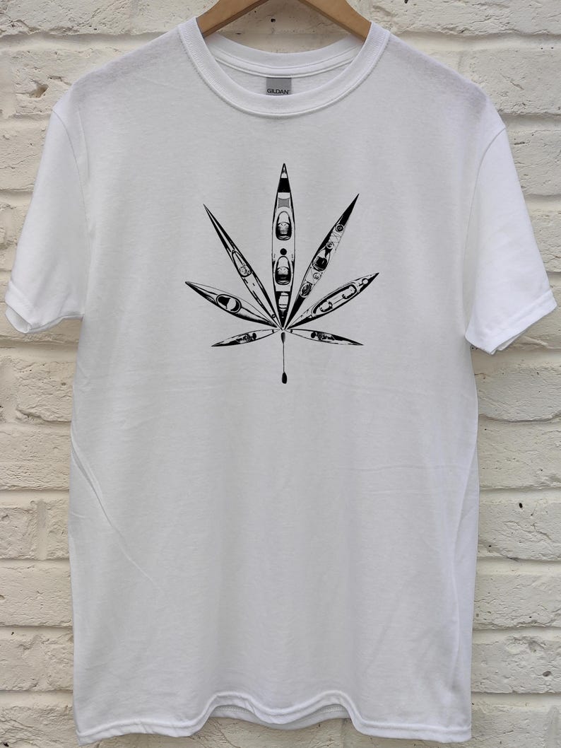 May include: White t-shirt featuring a black graphic of a cannabis leaf. The leaf design is composed of kayak illustrations. The shirt is made of a soft, comfortable material.
