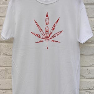 May include: White t-shirt featuring a red graphic of a cannabis leaf. The leaf design is composed of red kayak illustrations. The shirt is made of a soft, comfortable material.