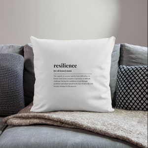 May include: White throw pillow with the word "resilience" and its definition printed in black text.