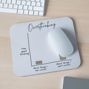 May include: A white mousepad with a black line graph depicting the amount of time spent thinking about things you can control versus things you can't control. The text "Overthinking" is written at the top of the graph.