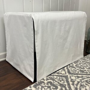 May include: White rectangular dog bed cover with a black trim. The cover is made of a soft, smooth fabric and has a simple, modern design.