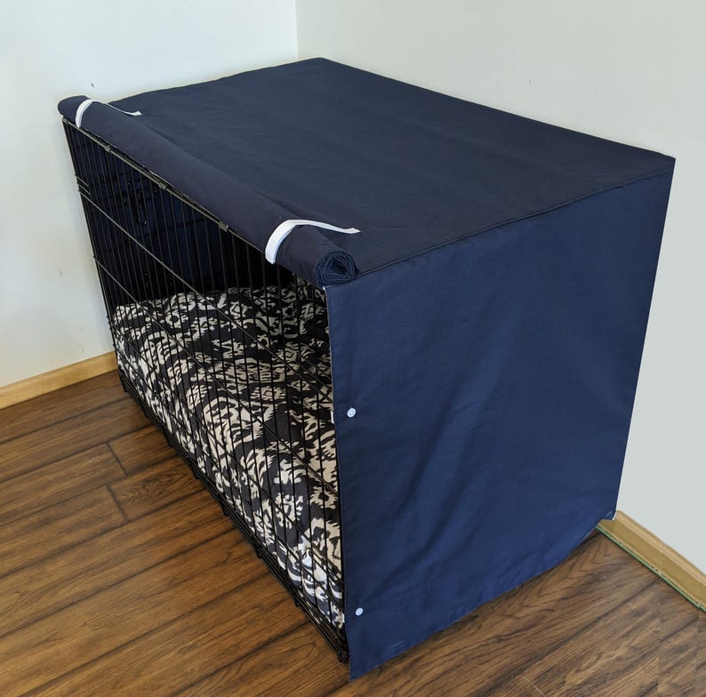 May include: A navy blue dog crate cover with a white trim. The cover is made of a soft, durable fabric and has a zippered opening for easy access. The cover is designed to provide privacy and a sense of security for your pet.