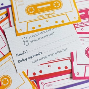 K&ouml;nnte beinhalten: Eine wei&szlig;e RSVP-Karte mit einem gelben und roten Kassettenband-Design. Die Karte enth&auml;lt einen Bereich f&uuml;r die Namen der G&auml;ste, di&auml;tetische Anforderungen und eine Songanfrage. Der Text "Wir w&uuml;rden es f&uuml;r die Welt nicht verpassen. Wir werden im Geiste dabei sein." ist auf der Karte gedruckt. Die Karte enth&auml;lt auch den Text "Bitte antworten Sie bis zum 28. August 2020."