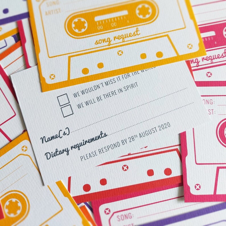 K&ouml;nnte beinhalten: Eine wei&szlig;e RSVP-Karte mit einem gelben und roten Kassettenband-Design. Die Karte enth&auml;lt einen Bereich f&uuml;r die Namen der G&auml;ste, di&auml;tetische Anforderungen und eine Songanfrage. Der Text "Wir w&uuml;rden es f&uuml;r die Welt nicht verpassen. Wir werden im Geiste dabei sein." ist auf der Karte gedruckt. Die Karte enth&auml;lt auch den Text "Bitte antworten Sie bis zum 28. August 2020."