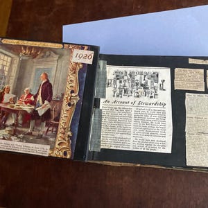 May include: An open scrapbook with a black cover. The pages are filled with newspaper clippings and images. The scrapbook includes the years 1776 and 1926. The text on the page reads "An Account of Stewardship".