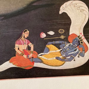 May include: A traditional Indian painting depicting a reclining blue-skinned deity with a crown and jewelry, being attended to by a woman in a red and gold sari. The deity is lying on a white serpent with a multi-headed hood.