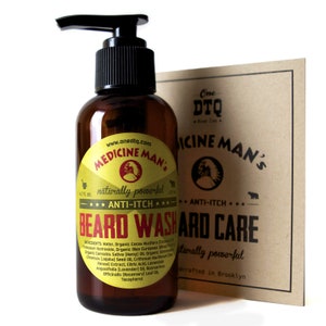 May include: A brown glass bottle with a pump dispenser containing beard wash. The label is yellow and red with the text "Medicine Man's" and "Naturally Powerful Anti-Itch Beard Wash". The bottle is sitting on a brown surface next to a brown card with the text "One DTQ Medicine Man's Anti-Itch Beard Care Naturally Powerful Handcrafted in Brooklyn".