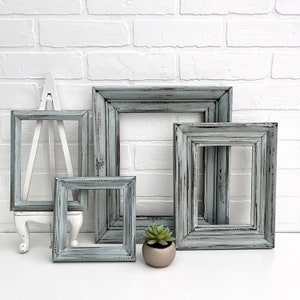 May include: Four distressed gray picture frames of varying sizes, with a small succulent plant in a gray pot in the foreground.