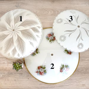 May include: Three vintage glass ceiling light shades. One shade features a white and gray floral design, another has a scalloped edge with a gray floral pattern, and the third has a floral and gold rim design with floral accents.