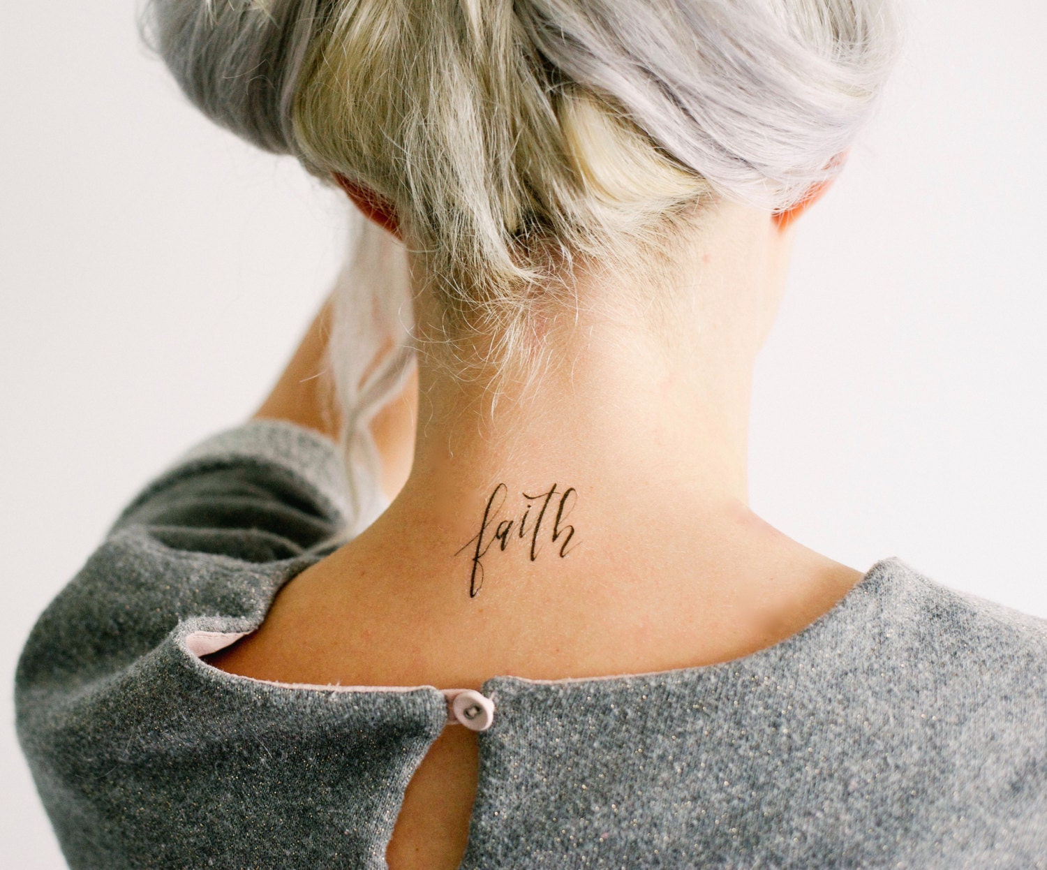 FAITH lettering tattoo on the back of the neck