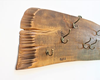 May include: A rustic wooden wall-mounted coat rack with a natural wood finish and multiple brass hooks. The rack has a unique, irregular shape and a distressed look. The text "PROJECT 6" is visible on the rack.