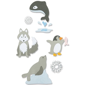 Puede incluir: Un conjunto de recortes de papel con animales árticos, incluyendo un lobo, un pingüino sosteniendo un pez, una foca en un iceberg y una ballena saltando fuera del agua. También hay dos diseños de copos de nieve.
