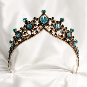 May include: A gold crown with blue gemstones and black accents. The crown is on a white background.
