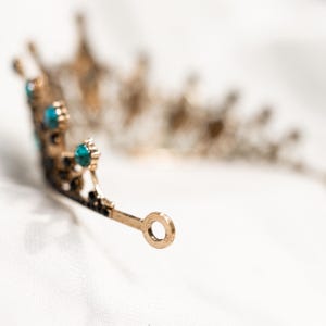 May include: A gold tiara with blue gemstones. The tiara has a delicate design and is perfect for a special occasion.