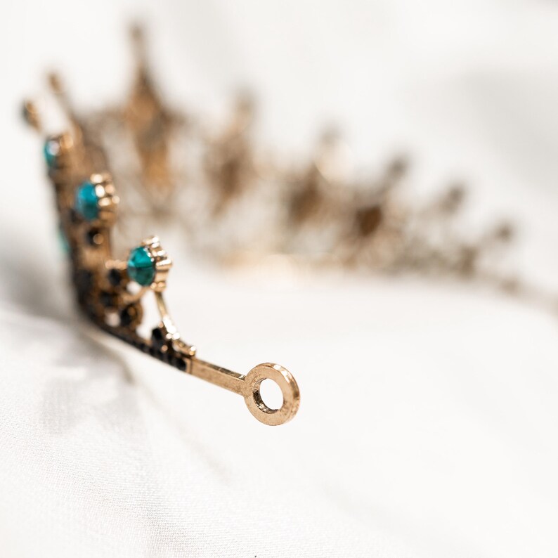 May include: A gold tiara with blue gemstones. The tiara has a delicate design and is perfect for a special occasion.
