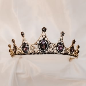 May include: A gold crown with purple gemstones. The crown has a delicate design with intricate details.
