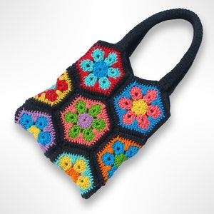 Könnte beinhalten: Eine schwarze gehäkelte Tragetasche mit bunten Blumendesigns. Die Tasche hat einen einzigen Henkel und ist aus Garn gefertigt.